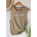 Brown tank top with 'be the light' text on a hanger against a neutral background