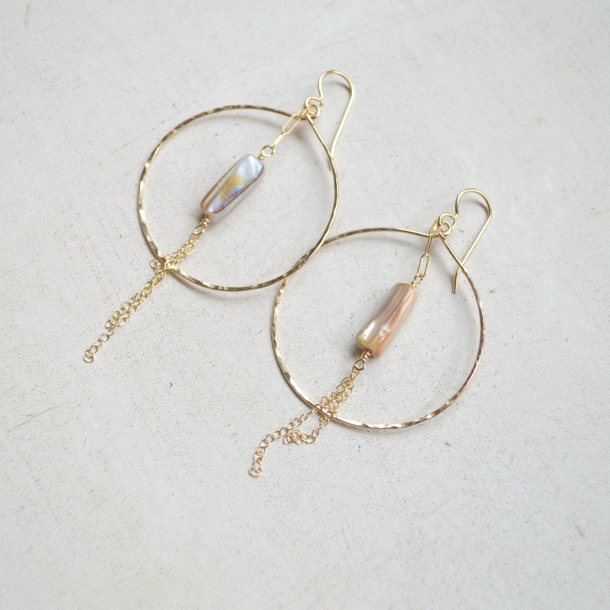Gold hoop earrings with pearl-like beads on a light gray background
