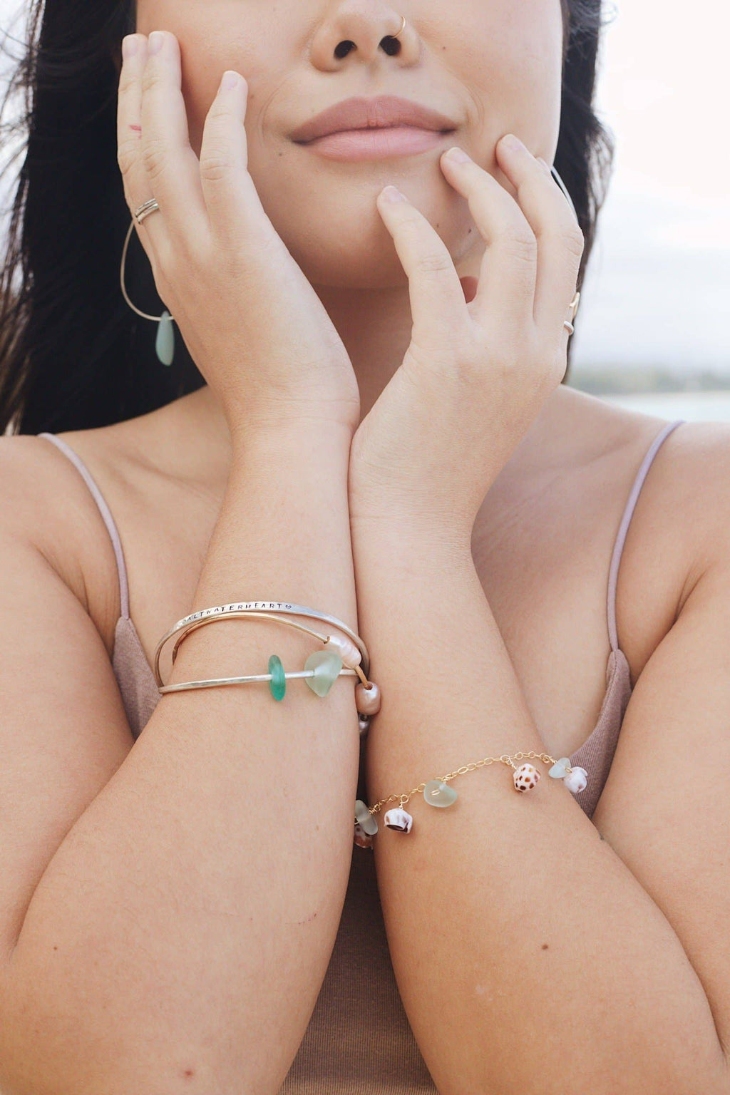 Woman wearing multiple bracelets on her wrists with a blurred background