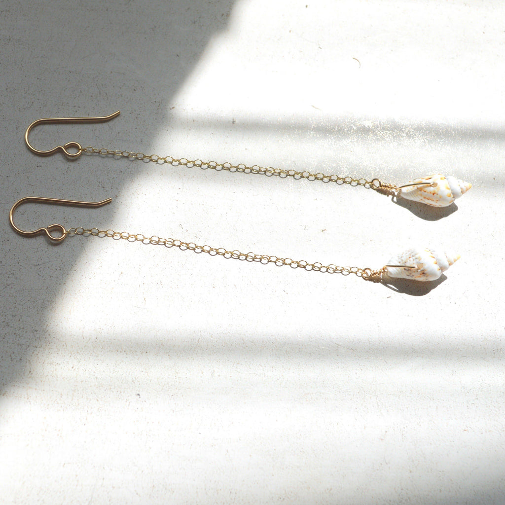 Gold chain earrings with crystal-like ends on a light surface