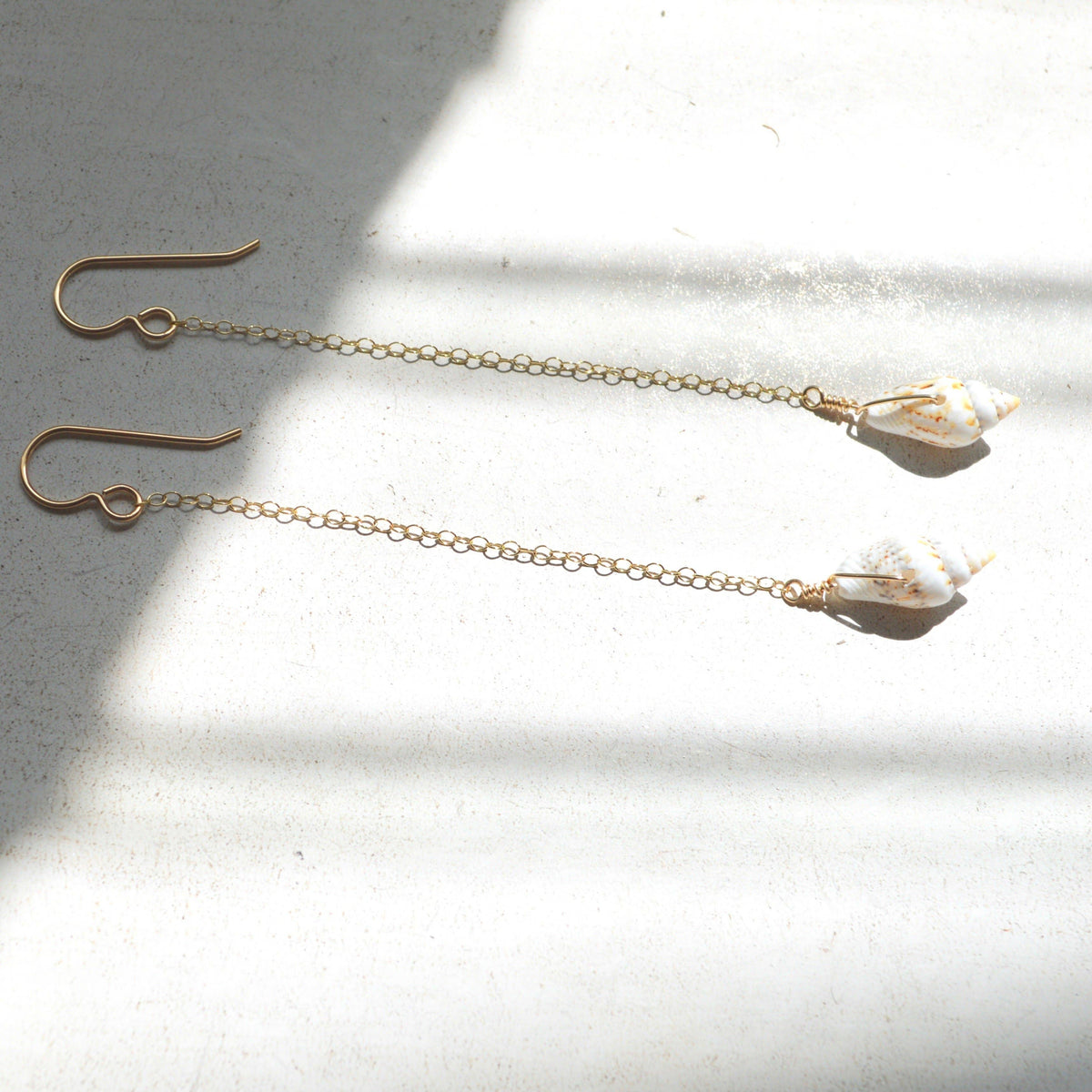 Gold chain earrings with crystal-like ends on a light surface