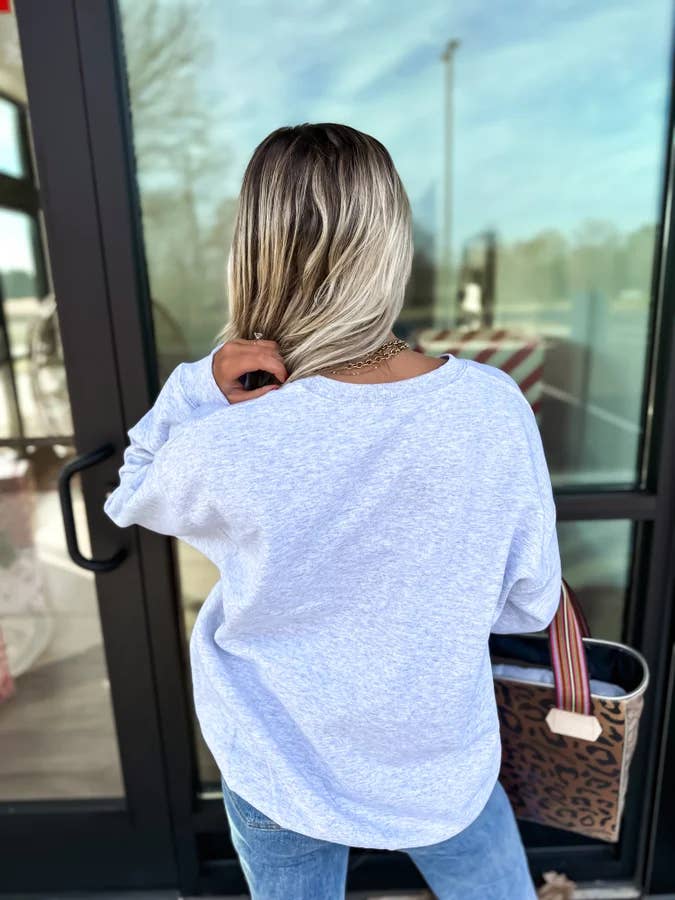 Person wearing a light blue oversized shirt standing in front of a glass door.