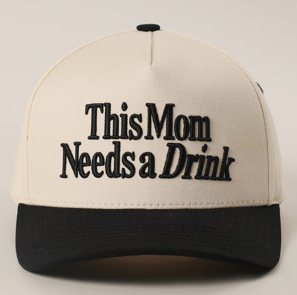 Beige and black cap with 'This Mom Needs a Drink' text on a light gray background