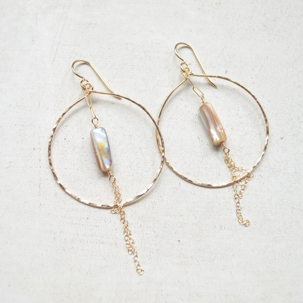 Gold hoop earrings with pearl-like beads on a light background
