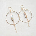 Gold hoop earrings with pearl-like beads on a light background