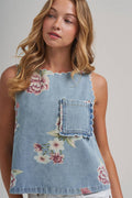 Woman wearing a denim top with floral patterns on a plain background
