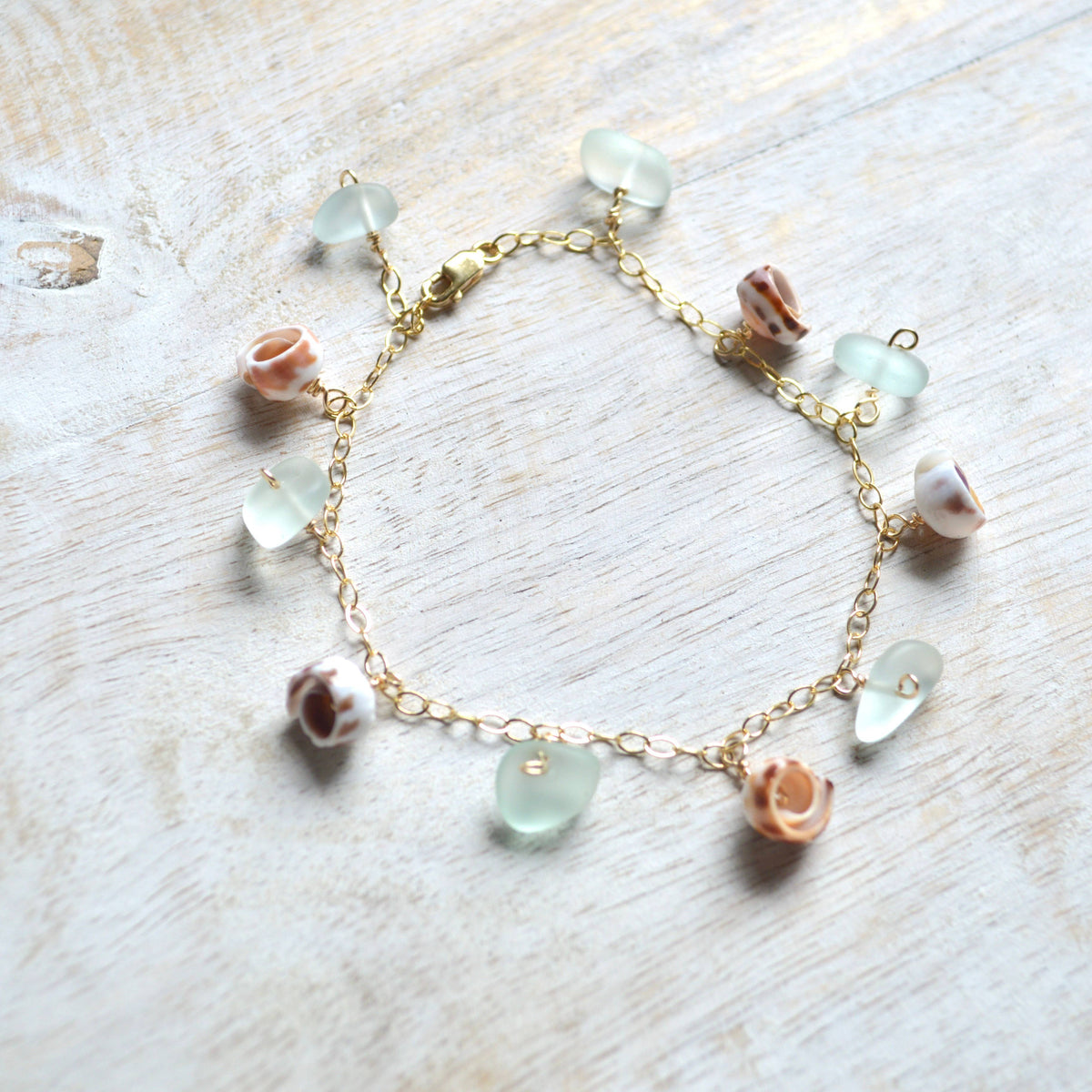 Bracelet with green and pink beads on a light wooden surface