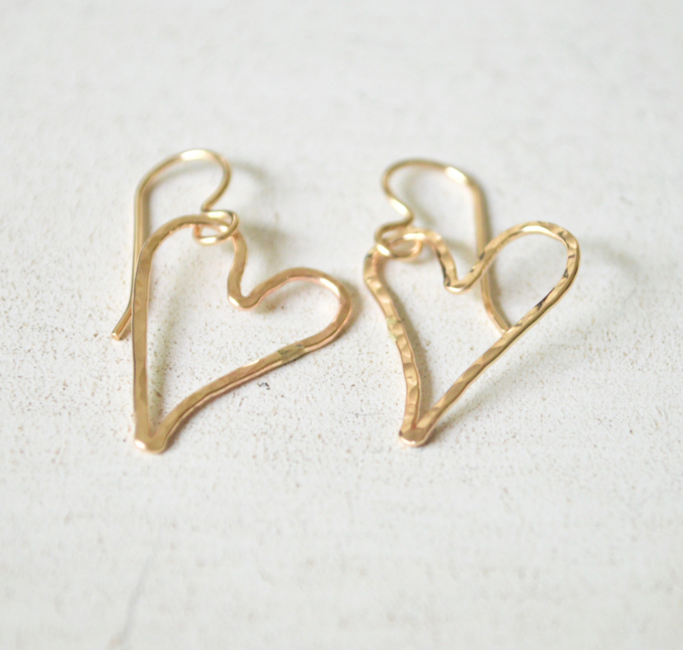 Gold heart-shaped earrings on a light background