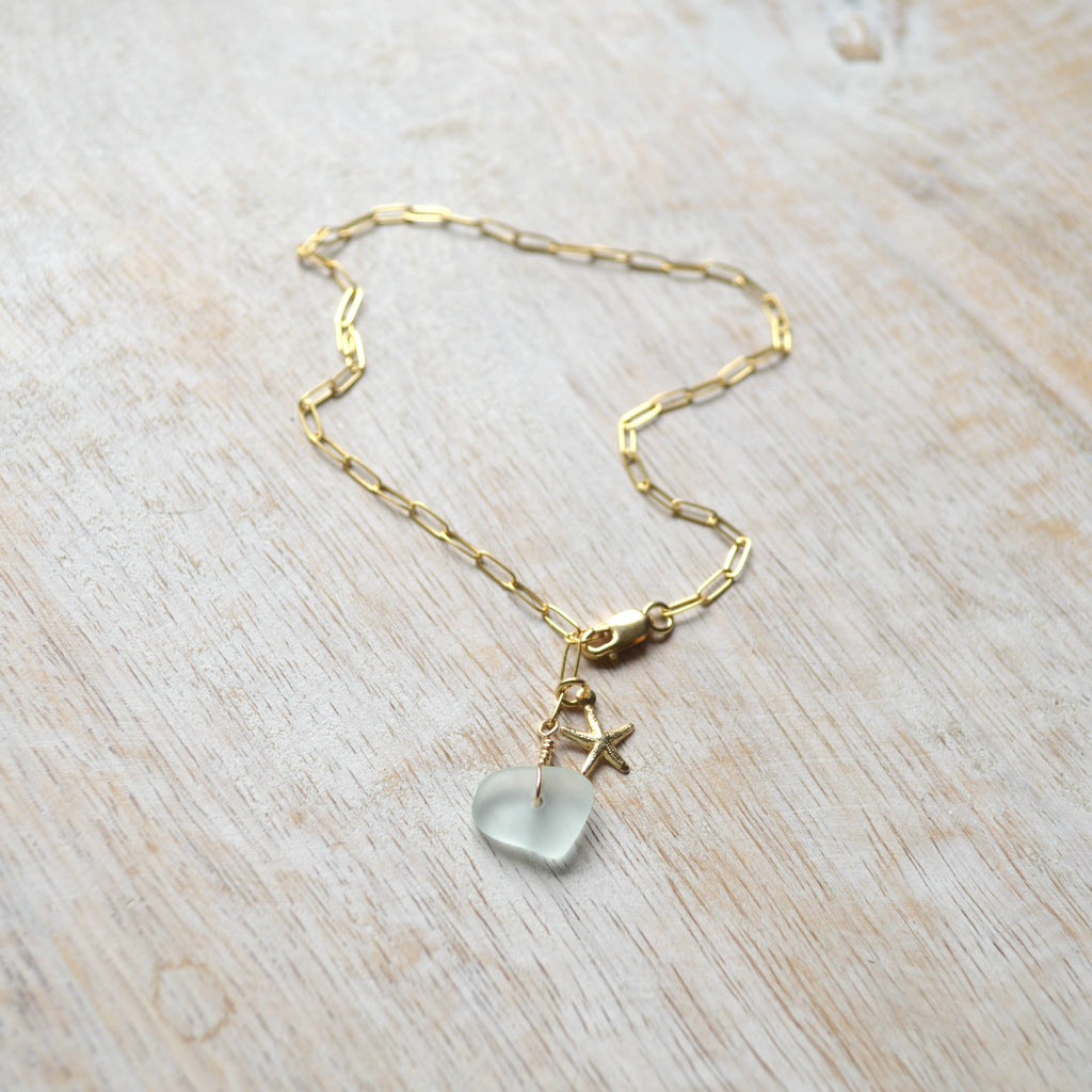 Gold necklace with a heart-shaped pendant on a light wooden surface