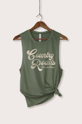 An olive green sleeveless tank top with a distressed cream graphic reading 'Country Roads Take Me Home', hanging on a wooden hanger against a light beige background.