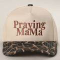 Beige cap with 'Praying MaMa' text and camouflage pattern on a light gray background