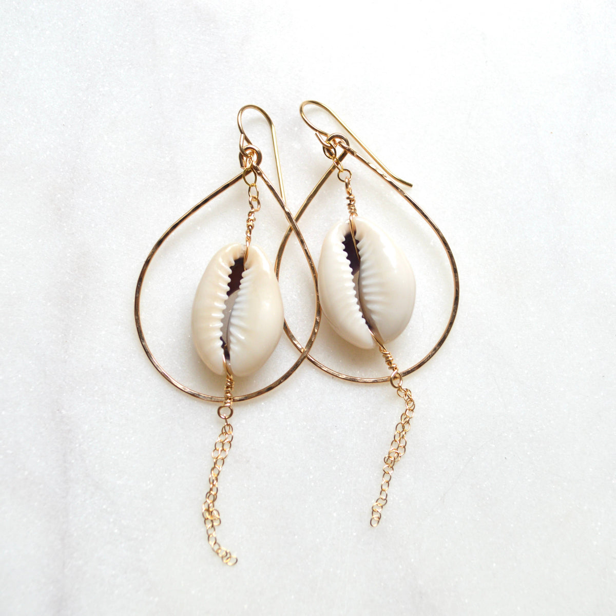 Pair of earrings with cowrie shells on a white background