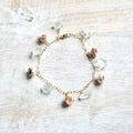 Bracelet with sea glass and shell charms on a light wooden surface