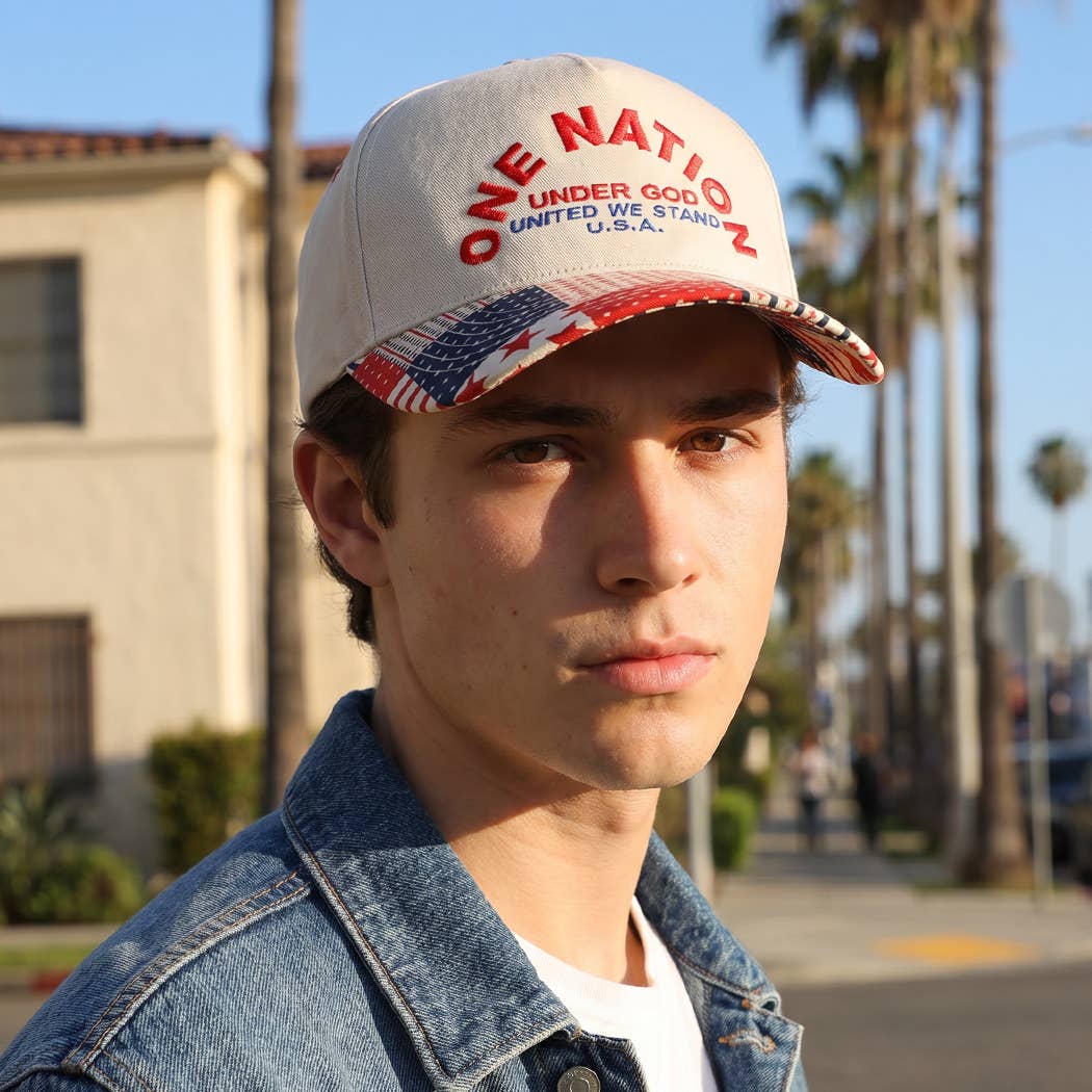 Person wearing a cap with 'One Nation Under God' text and American flag design, standing outdoors.