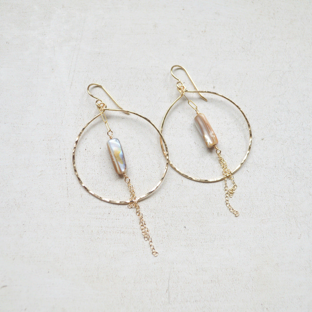 Gold hoop earrings with pearl-like beads on a light background