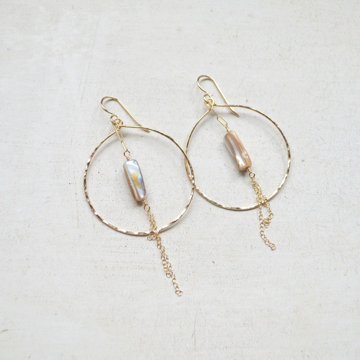 Gold hoop earrings with pearl-like beads on a light background