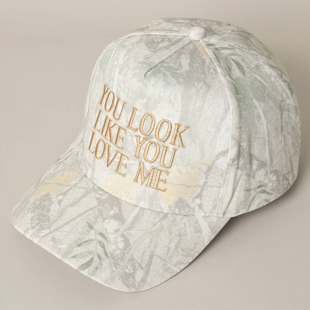 Marble-patterned cap with gold text 'YOU LOOK LIKE YOU LOVE ME' on a beige background