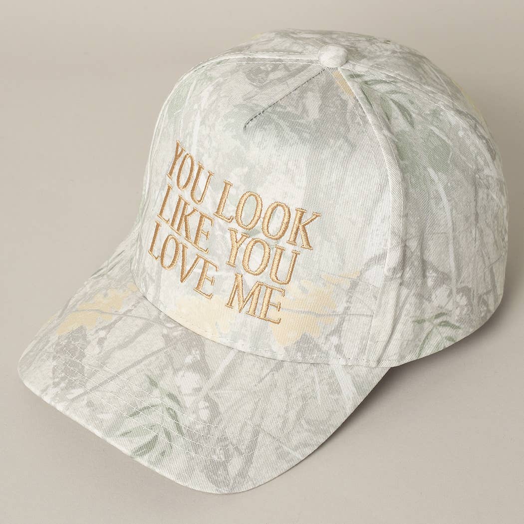 Marble-patterned cap with gold text 'YOU LOOK LIKE YOU LOVE ME' on a beige background