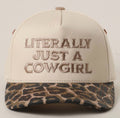 A beige snapback cap with brown embroidered text reading 'LITERALLY JUST A COWGIRL' on the front, featuring a leopard-print patterned visor.